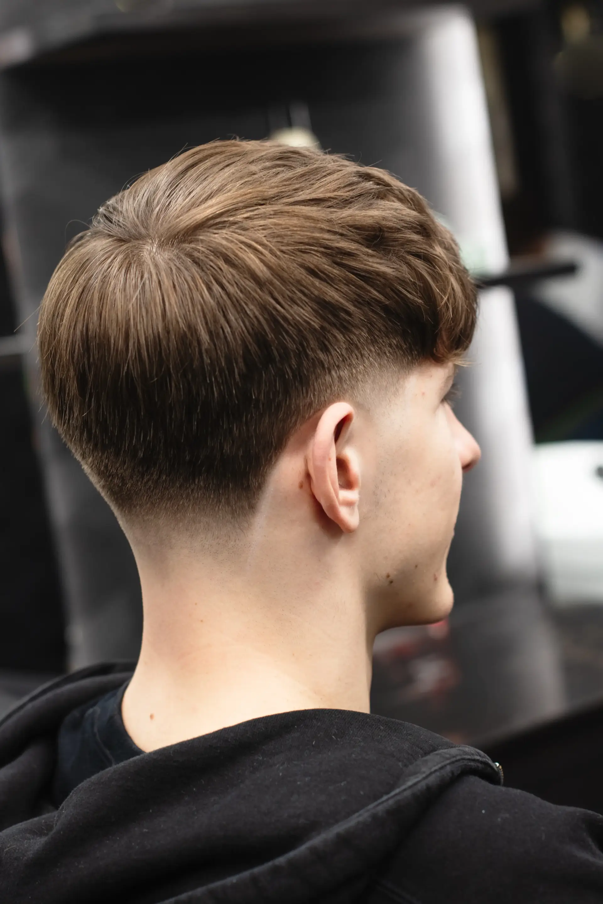 Rear view of a man’s textured crop haircut, featuring a neat tapered neckline and a smooth transition from the crown to the nape. The hairstyle showcases a modern, low-maintenance look with subtle volume and clean lines.